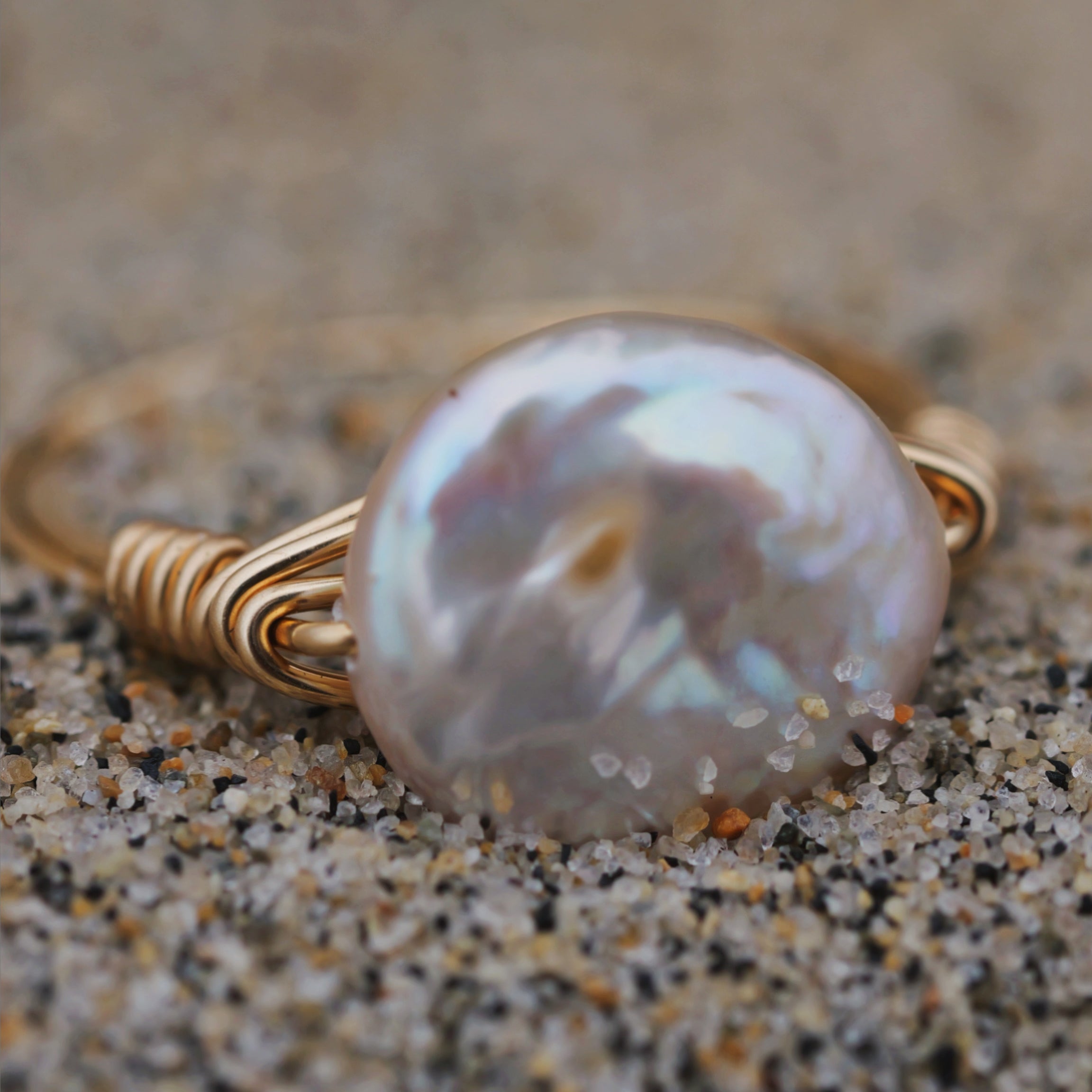 Gold pearl circle ring in the sand